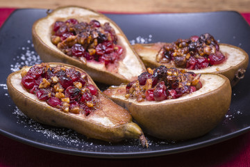 Homemade baked pears with honey, red cranberries and walnuts, close up