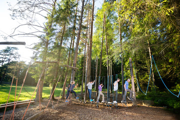 Fototapeta na wymiar Multiethnic Coworkers Crossing Swinging Logs In Forest