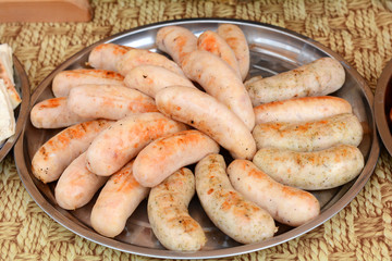 Fresh sausage and hot dogs grilling outdoors on a gas barbecue grill. Closeup of sausage on the grill