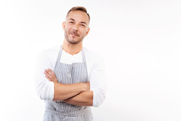 Smiling man in apron folding his arms across chest