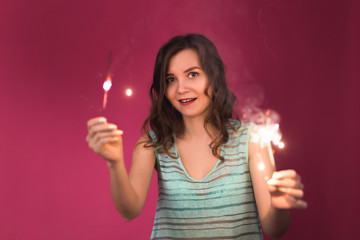 Fototapeta premium Young woman having fun with a sparkler. Christmas, new year and holidays concept