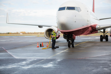 Worker Charging Airplane On Wet Airport Runway