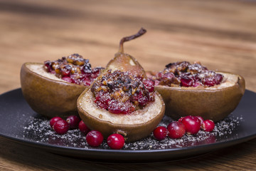 Homemade baked pears with honey, red cranberries and walnuts, close up