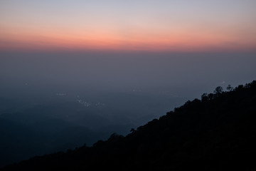 Sunset scene on hight mountain. Sunshine through the clouds. silhouette at the mountain.
