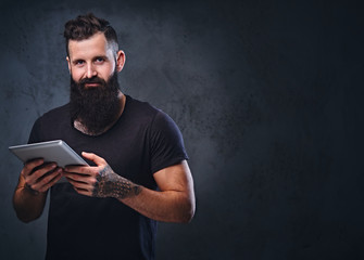 A man holds silver tablet PC over grey background.