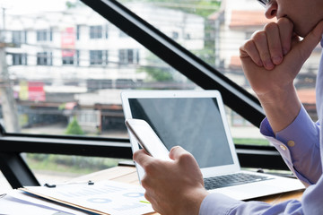 thoughtful businessman use mobile phone at workplace. man texting message on smart phone at office. employee use cellphone for online network connection.