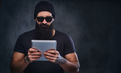 A man in a hat and sunglasses holds tablet PC.