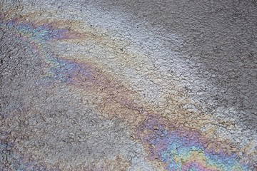 Öl schillert auf Asphalt in Regenbogenfarben