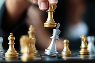 Close up shot hand of business woman moving golden chess to defeat and kill silver king chess on...