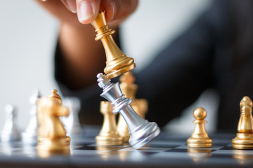 Close up shot hand of business woman moving golden chess to defeat and kill silver king chess on...