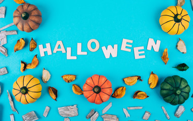 Decorative pumpkins on trendy blue background with fall leaves.