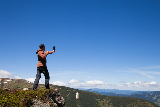 Man on the mountain top taking selfie by cell phone