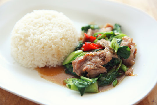 fried pork with Chinese Kale and rice on wood background , Thai food