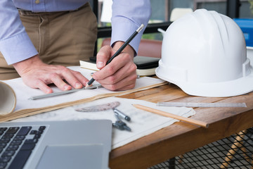 architect hand holding drawing compass working on construction plan at office. engineer inspect blueprint with divider at workplace. man sketching real estate project