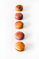 Close-up shot of passion fruit and espresso macarons, French meringue-based patissiere cookies filled with chocolate ganache and dusted with cocoa powder on white background