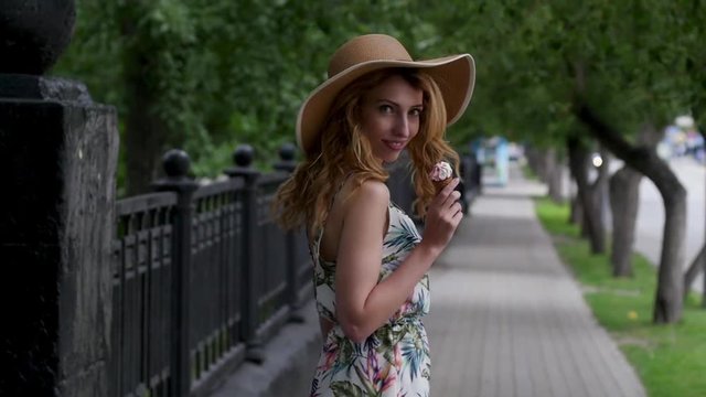beautiful young woman in a hat walking around the city with an ice cream