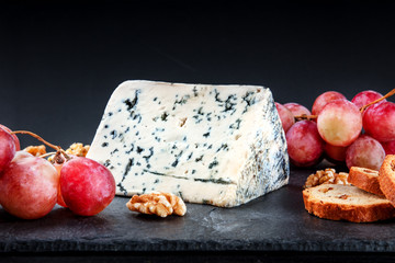 Blue cheese and grapes on black with copy space
