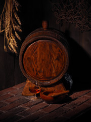 Glass of cognac with barrel in cozy cellar