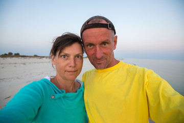 Funny couple of travelers taking selfie on the deserted seashore