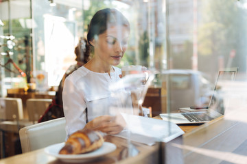 Sophisticated woman reading and drinking latte in cafe