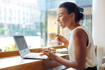 Young woman checking the application and drinking latte in cafe