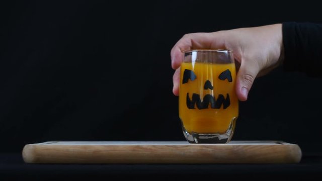 Halloween. Crawling hand grabs a glass.
