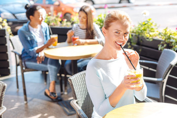 Charming woman posing while drinking smoothie in cafe