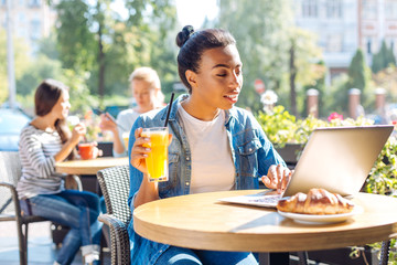 Cheerful woman holding a glass of juice while chatting