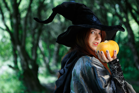 Portrait of witch in black hat with pumpkin