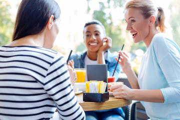 Two joyful women reacting to gossips of their friend