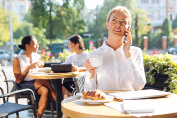 Cheerful woman talking on the phone on restaurant terrace