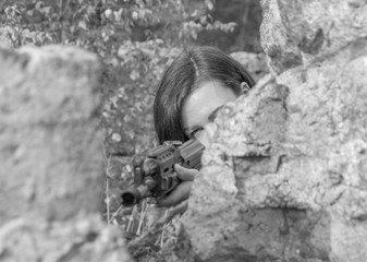 black and white, girl with a gun in his hands aiming for the stone.