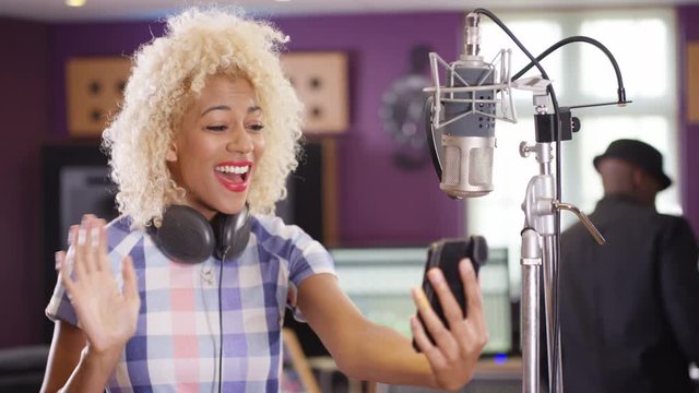  Female vocalist in recording studio using mobile phone for video call