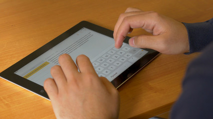 Close-up of male hands using modern digital tablet and computer at office, frontal view of businessman hands typing text information on touch screen of tablet pc