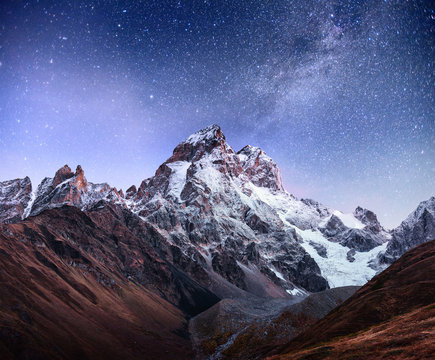 Fantastic starry sky. Autumn landscape and snow-capped peaks. Main Caucasian Ridge. Mountain View from Mount Ushba Meyer, Georgia. Europe