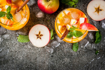 Traditional fall drinks, Apple cider mojito cocktails with mint, cinnamon and ice. On black stone...