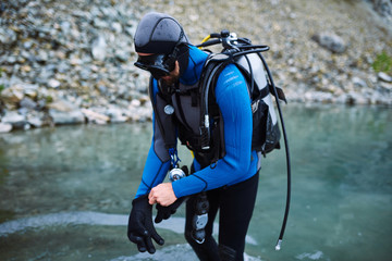 Male diver in wetsuit checking equipments before immerse