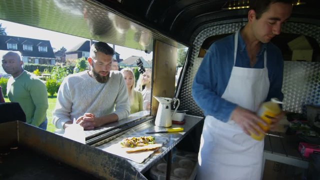  Cheerful food vendor in burger van serving customers at community event