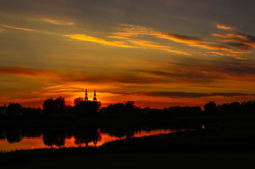 sunset over a river with a church