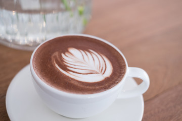 hot chocolate drink with leaf latte art. cocoa beverage on wood table.