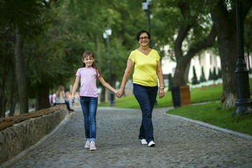 Obraz premium Grandmother with her granddaughter are walking in the park to hold hands