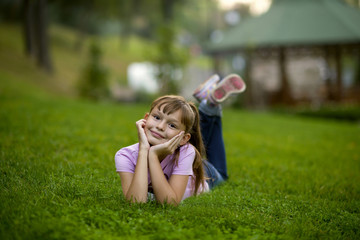 Little girl lies on the green grass in the park