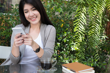 asian woman sit at outdoor cafe. young female adult use mobile phone at coffee shop. attractive teenager connect online network communication on smart phone. technology, lifestyle concept