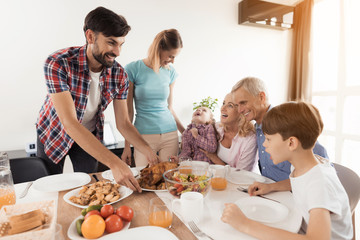 A man with a woman serves a festive dinner on the table, for Thanksgiving