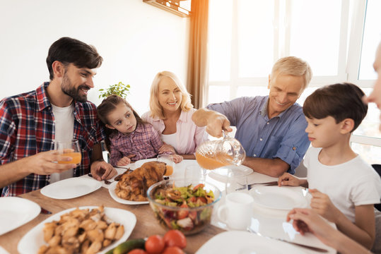 A man pours juice for his family, who gathered at a festive table for Thanksgiving - Powered by Adobe