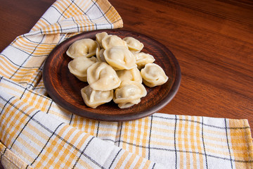 Boiled Ukrainian meat dumplings or ravioli on wooden background.