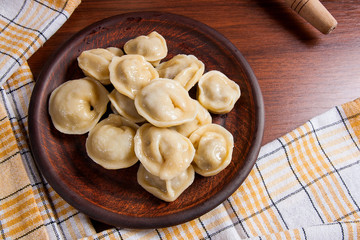 Boiled Ukrainian meat dumplings or ravioli on wooden background.