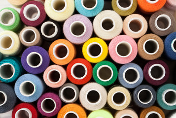 Background of colorful sewing threads on white table