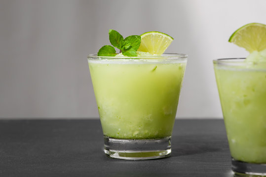 Cocktail juice with lime, mint and ice. Bar drink accessories on black table background.