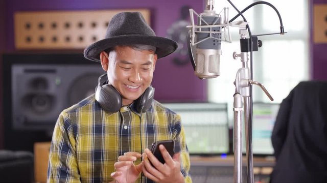  Male vocalist in recording studio using mobile phone for video call